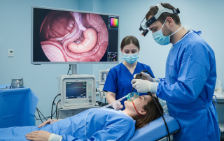 Doctor performing endoscopy with a thin tube and camera while the patient lies on a hospital bed.